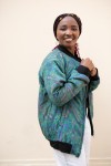 Vista lateral de chaqueta bomber de seda turquesa con estampado paisley y bolsillos laterales.