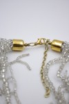 Cierre metálico dorado con cadena ajustable de un collar de cuentas plateadas.