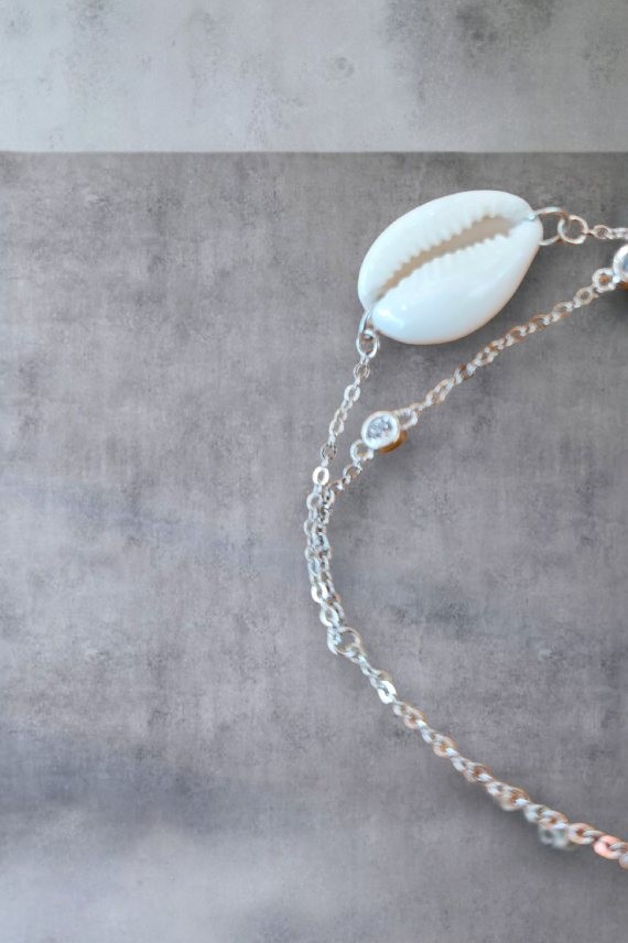Pulsera en plata de ley con doble cadena, concha cauri natural y dos circonitas blancas, diseño artesanal de Samarkanda. Pulsera en plata de ley con doble cadena, concha cauri natural y dos circonitas blancas, diseño artesanal de Samarkanda.