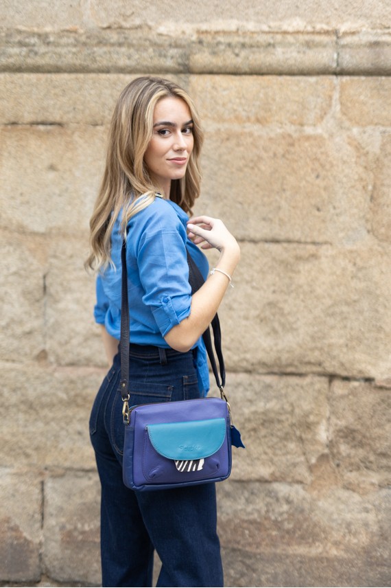 “Bolso Cher Soruka de piel reciclada en colores verde, azul y rojo, diseño artesanal sostenible con lengüeta reversible.”