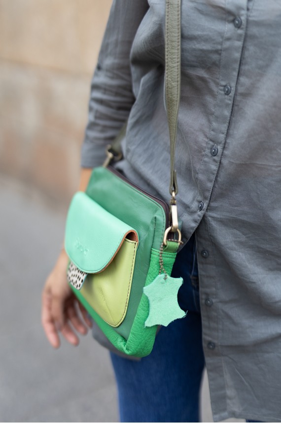 “Bolso Cher Soruka de piel reciclada en colores verde, azul y rojo, diseño artesanal sostenible con lengüeta reversible.”