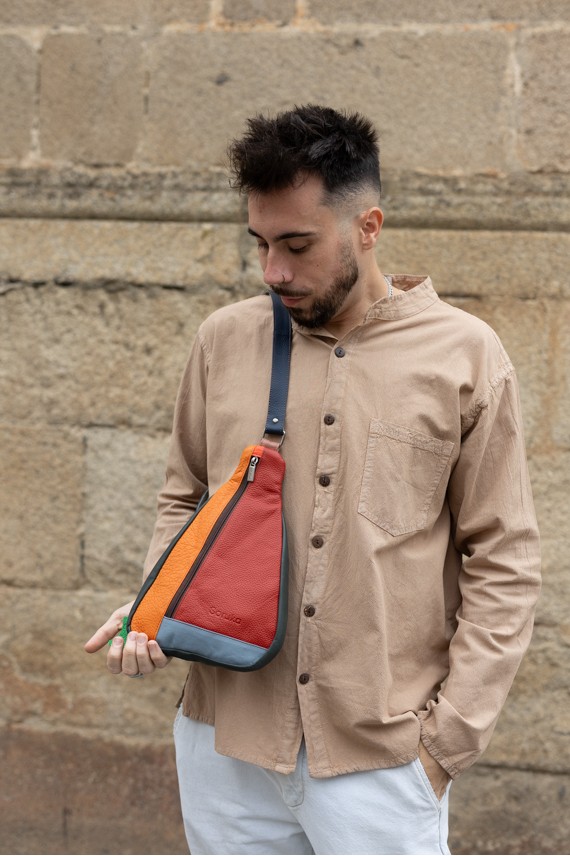 "Bolso bandolera unisex de piel sostenible Soruka en patchwork de tonos naranja, rojo y gris, diseño artesanal y ecológico