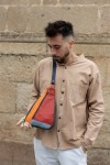 "Bolso bandolera unisex de piel sostenible Soruka en patchwork de tonos naranja, rojo y gris, diseño artesanal y ecológico