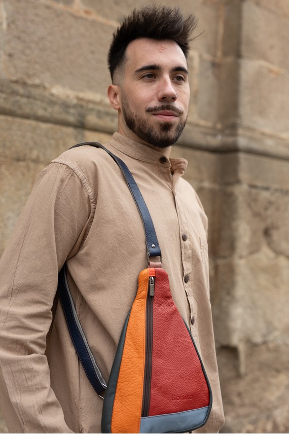 "Bolso bandolera unisex de piel sostenible Soruka en patchwork de tonos naranja, rojo y gris, diseño artesanal y ecológico