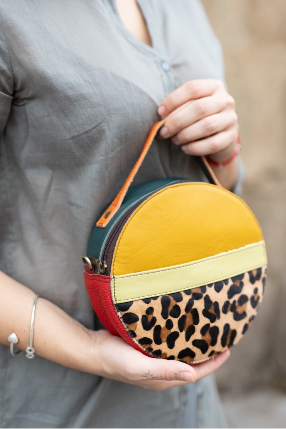 "Bolso Hera redondo de piel sostenible Soruka animal print de leopardo, en tonos mostaza, verde, beige y rojo.