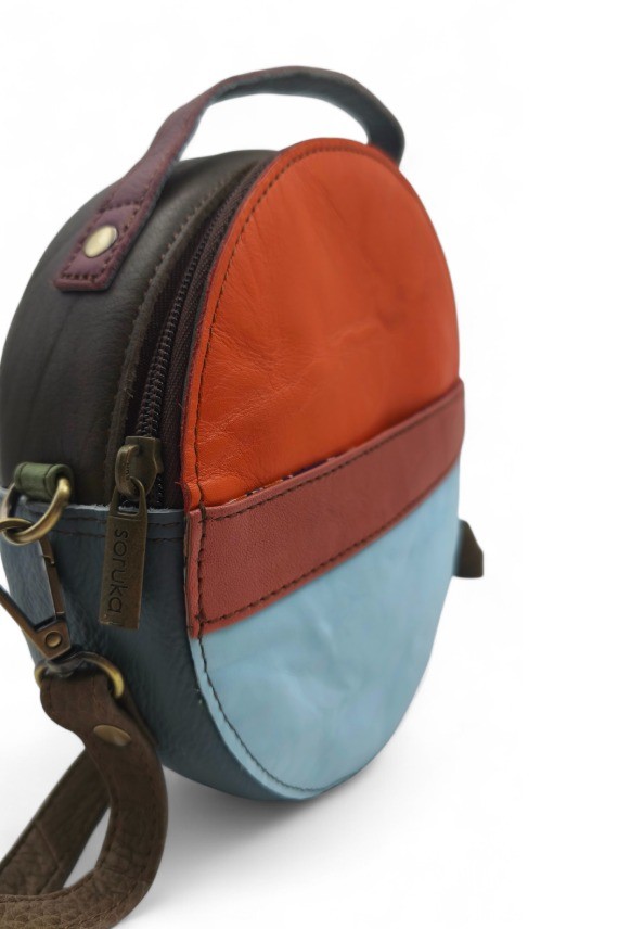 "Bolso Hera redondo de piel sostenible Soruka, diseño patchwork bicolor naranja y celeste