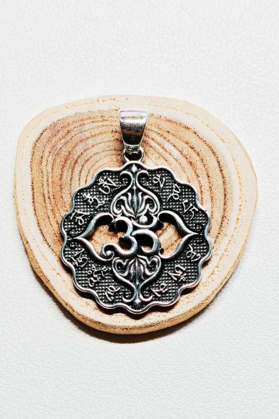 "Colgante de plata de ley 925 con símbolo Ohm y flor de loto, diseño circular artesanal de 3.2 cm."