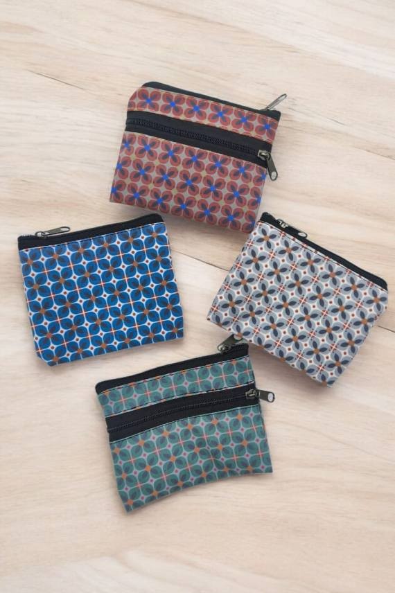 Monederos de tela con estampados geométricos en varios colores, cada uno con diseño compacto y doble cremallera.