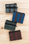 Monederos compactos de tela con estampado de líneas en varios colores y diseño de doble cremallera.