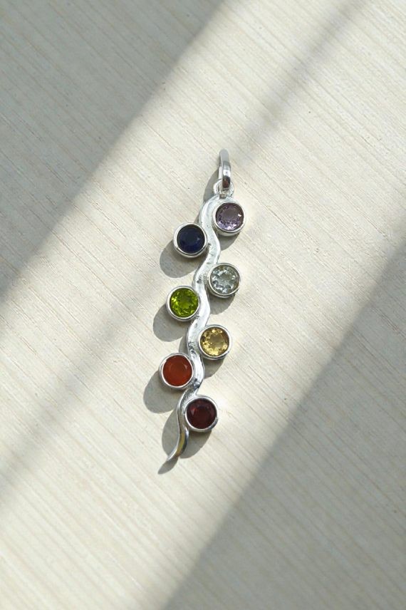 Colgante artesanal de plata con siete gemas de colores engastadas en un diseño ondulado