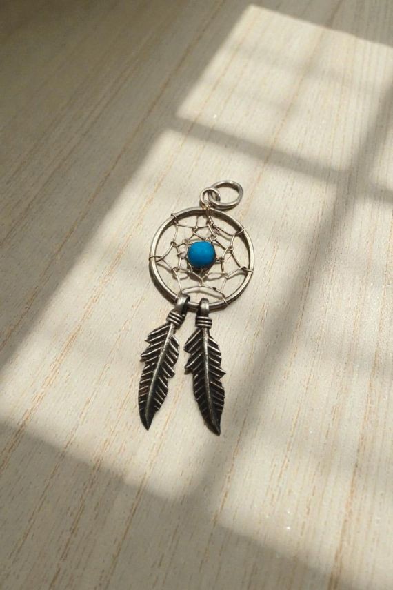 Colgante artesanal de plata con diseño de atrapasueños, piedra turquesa central y dos plumas colgantes