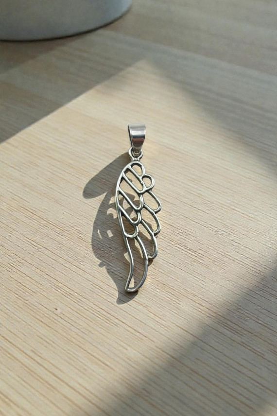 "Colgante de plata de ley con ala de ángel calada tallada a mano, diseño boho espiritual."