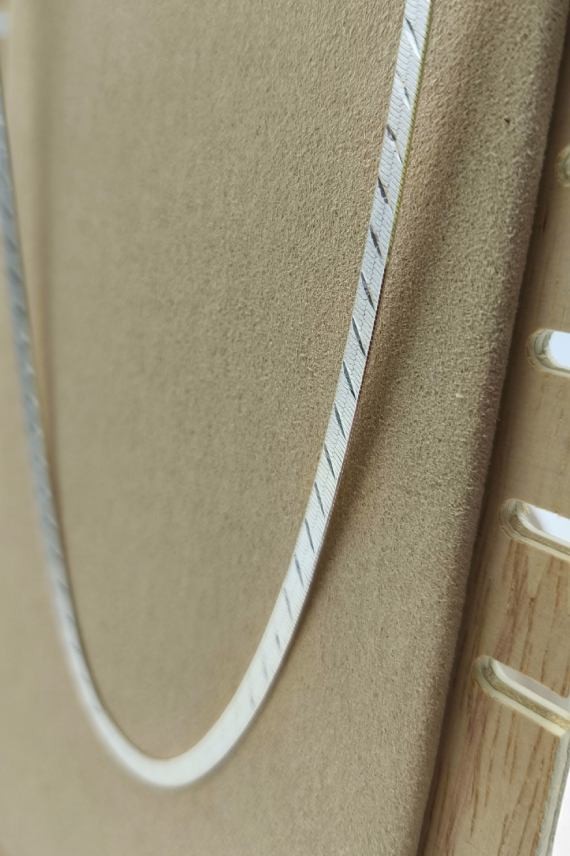 Collar de plata con cadena plana texturizada, destacando su grabado delicado y acabado pulido.