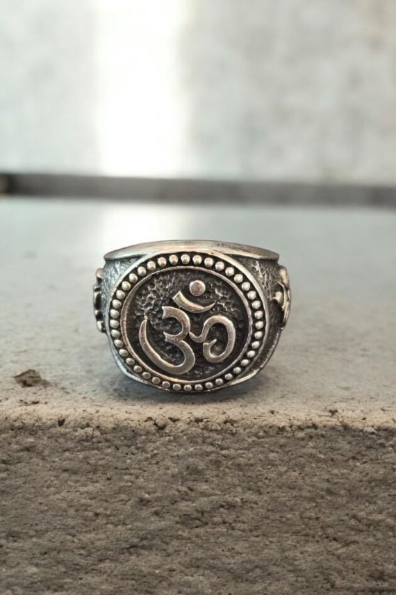Anillo de plata con símbolo Om en relieve y acabado envejecido, destacando su diseño artesanal y detalles decorativos.
