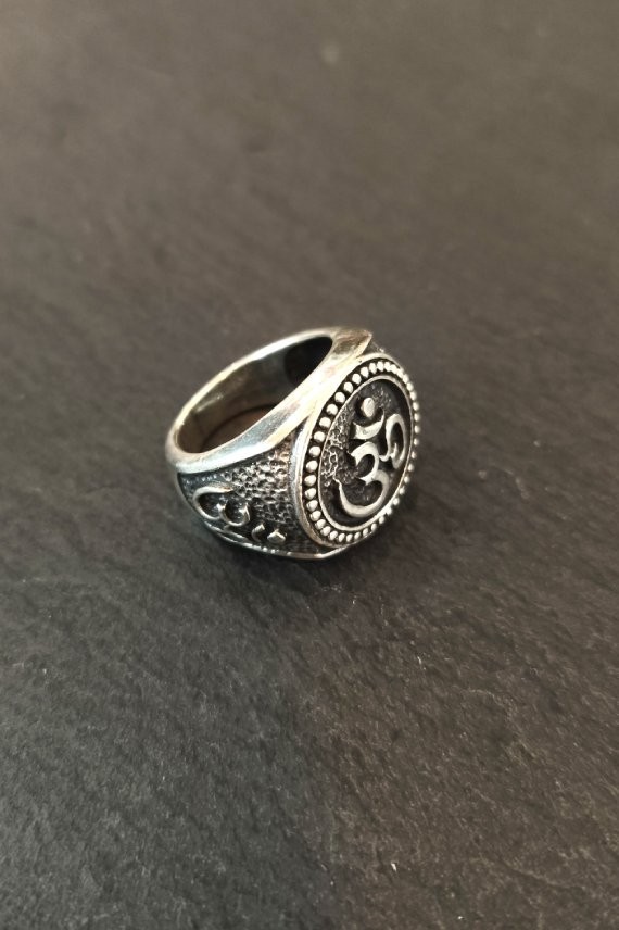 Anillo de plata con símbolo Om en relieve y acabado envejecido, destacando su diseño artesanal y detalles decorativos.