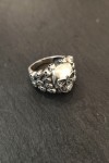 Anillo plateado con calavera central y laterales decorados con pequeñas calaveras
