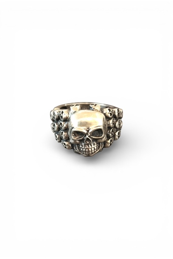 Anillo plateado con calavera central y laterales decorados con pequeñas calaveras