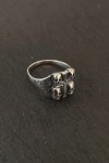 Anillo plateado con cruz central y calaveras en relieve