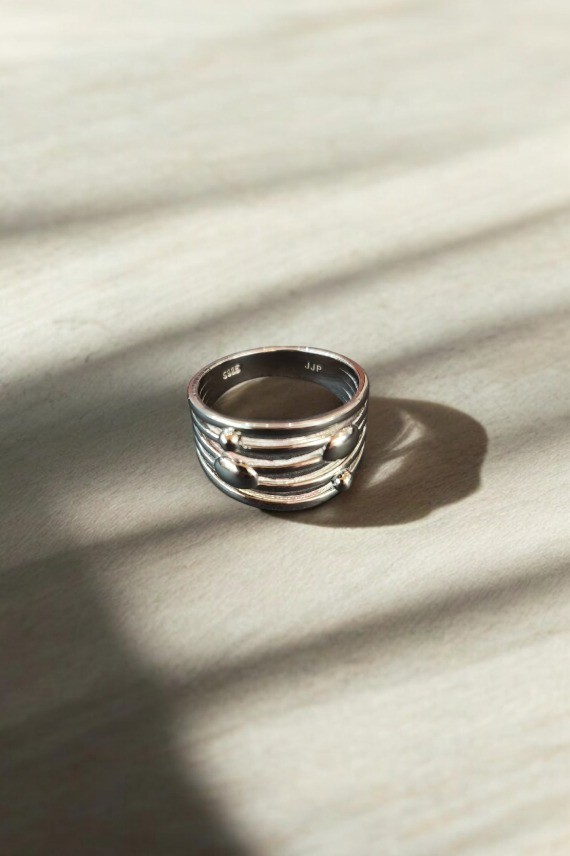 Anillo unisex de plata de ley con diseño de líneas paralelas en relieve y pequeños detalles esféricos, estilo moderno.