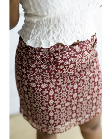 Falda corta burdeos con estampado floral beige y cinturón integrado con hebilla metálica, prenda boho chic para mujer.