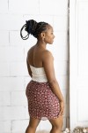 Falda corta burdeos con estampado floral beige y cinturón integrado con hebilla metálica, prenda boho chic para mujer.