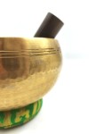 Cuenco tibetano artesanal de latón con mazo de madera y cojín decorativo para meditación, yoga y relajación.