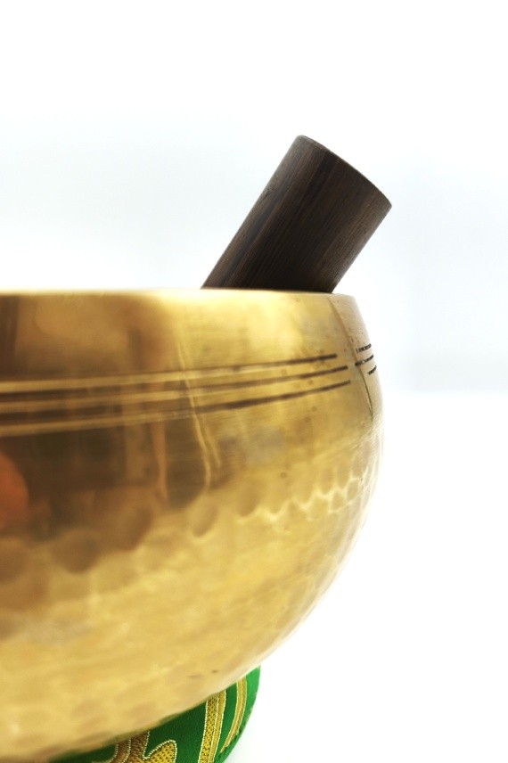 Cuenco tibetano artesanal de latón con mazo de madera y cojín decorativo para meditación, yoga y relajación.