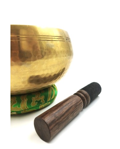Cuenco tibetano artesanal de latón con mazo de madera y cojín decorativo para meditación, yoga y relajación.