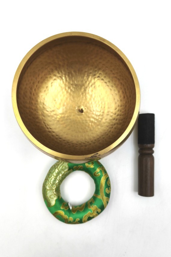 Cuenco tibetano artesanal de latón con mazo de madera y cojín decorativo para meditación, yoga y relajación.