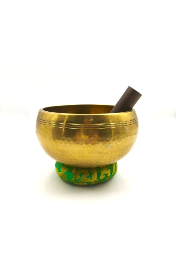Cuenco tibetano artesanal de latón con mazo de madera y cojín decorativo para meditación, yoga y relajación.