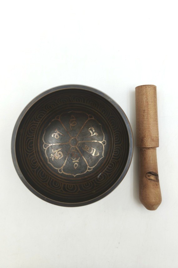 Cuenco tibetano artesanal con símbolo Om Mani, mantras grabados, mazo de madera y cojín decorativo para meditación y relajación.