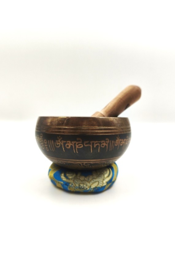Cuenco tibetano artesanal con símbolo Om Mani, mantras grabados, mazo de madera y cojín decorativo para meditación y relajación.