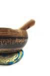 Cuenco tibetano artesanal con símbolo Om Mani, mantras grabados, mazo de madera y cojín decorativo para meditación y relajación.