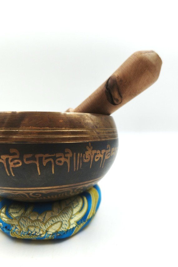 Cuenco tibetano artesanal con símbolo Om Mani, mantras grabados, mazo de madera y cojín decorativo para meditación y relajación.