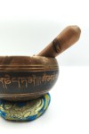 Cuenco tibetano artesanal con símbolo Om Mani, mantras grabados, mazo de madera y cojín decorativo para meditación y relajación.
