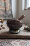 Cuenco tibetano artesanal con símbolo Om Mani, mantras grabados, mazo de madera y cojín decorativo para meditación y relajación.