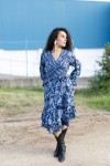 Vestido pareo midi boho azul en movimiento, con estampado vegetal, manga larga y falda fluida.