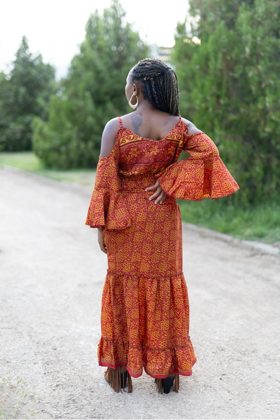 Vista trasera de vestido largo boho de seda y viscosa con estampado terracota y amarillo y mangas acampanadas.