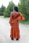 Vista trasera de vestido largo boho de seda y viscosa con estampado terracota y amarillo y mangas acampanadas.