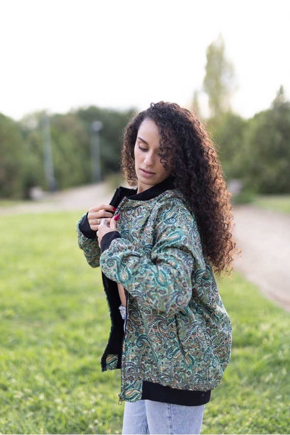 Vista lateral de chaqueta bomber de seda estampada en tonos verde agua, turquesa y azul.