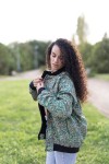 Vista lateral de chaqueta bomber de seda estampada en tonos verde agua, turquesa y azul.