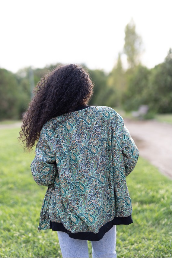 Vista trasera de chaqueta bomber de seda con estampado paisley multicolor en tonos verdes y azules.