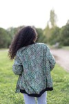 Vista trasera de chaqueta bomber de seda con estampado paisley multicolor en tonos verdes y azules.