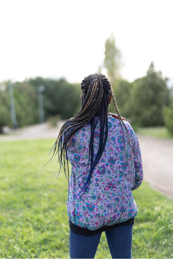 Vista trasera de chaqueta bomber de seda lila con estampado floral fucsia, azul, turquesa y verde.