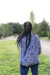 Vista trasera de chaqueta bomber de seda lila con estampado floral fucsia, azul, turquesa y verde.