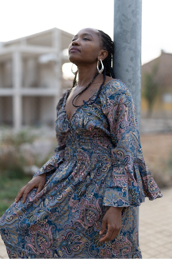 Detalle de vestido boho azul grisáceo con estampado paisley rosa y mostaza, cintura de nido de abeja y manga fluida.
