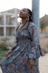 Detalle de vestido boho azul grisáceo con estampado paisley rosa y mostaza, cintura de nido de abeja y manga fluida.