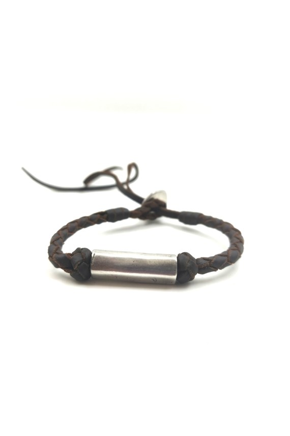 Pulsera Nómada de cuero marrón trenzado con pieza tubular de metal plateado y cierre ajustable.