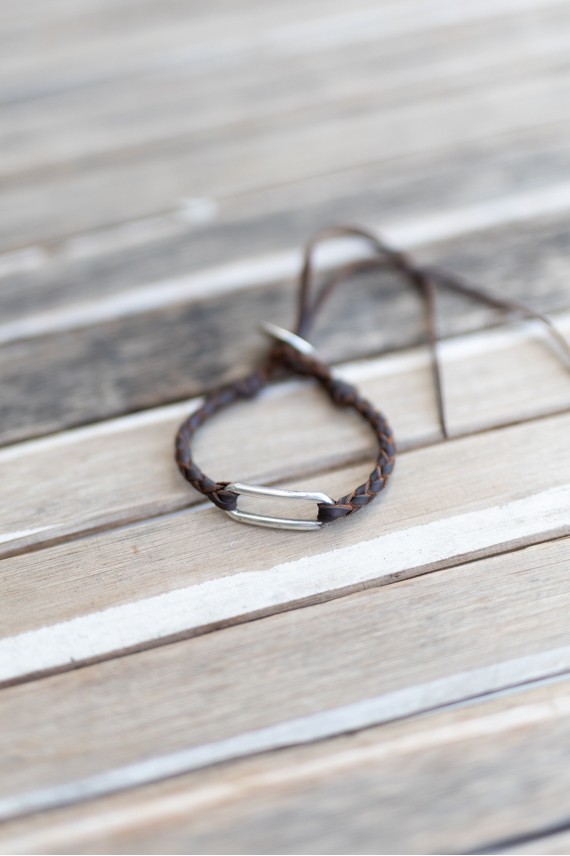 Pulsera Camino de cuero marrón trenzado con eslabón metálico alargado de acabado plateado.
