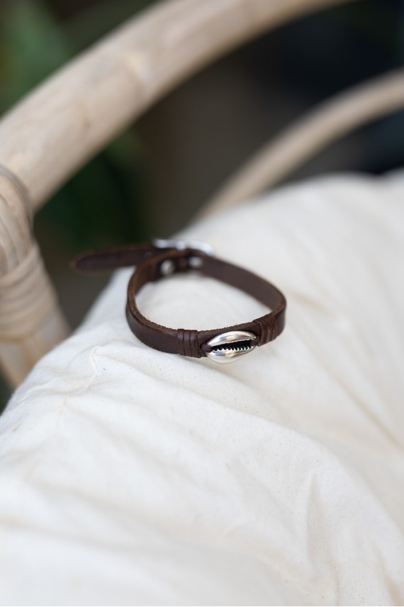 Pulsera Océano de cuero marrón con concha cauri metálica plateada y cierre de hebilla.